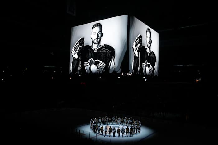 Oct 30, 2023; Pittsburgh, Pennsylvania, USA; Members of the Anaheim Ducks and the Pittsburgh Penguins stand at center ice for a moment of silence at the PPG Paints Arena to honor former Penguin forward Adam Johnson (on scoreboard) who was tragically killed in a hockey related accident in Europe.